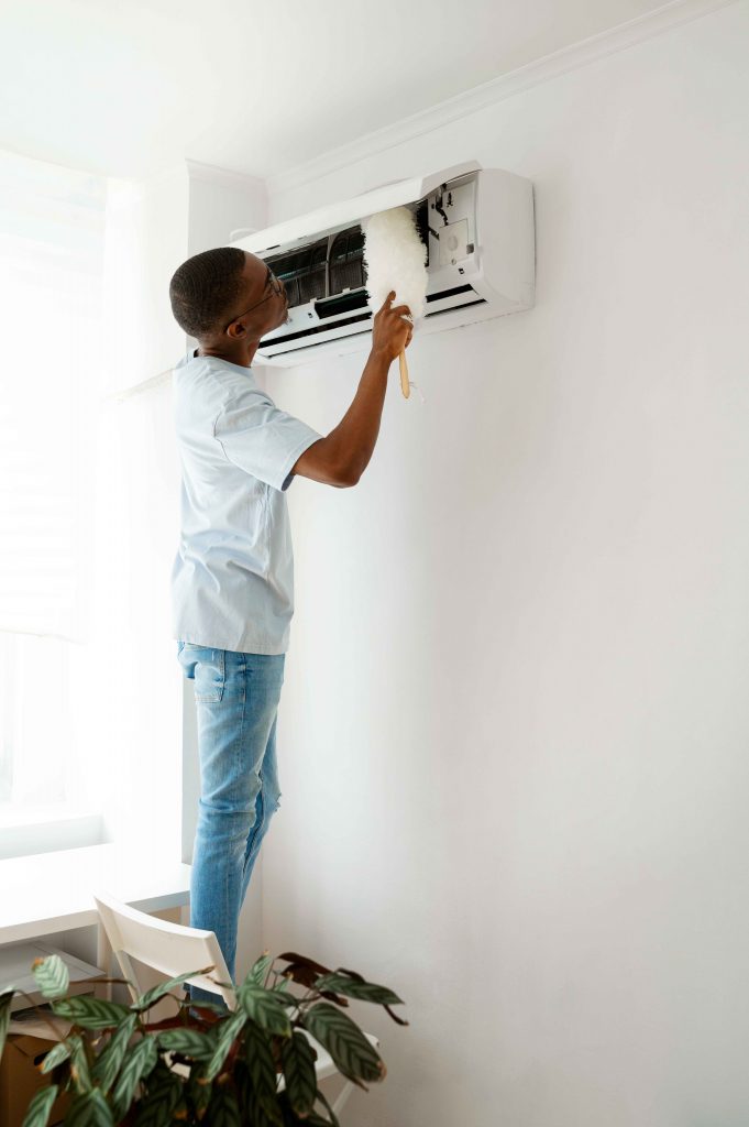 Ultimate guide to choosing the perfect ac unit 1 A man cleaning the filter of an air conditioning unit with a brush